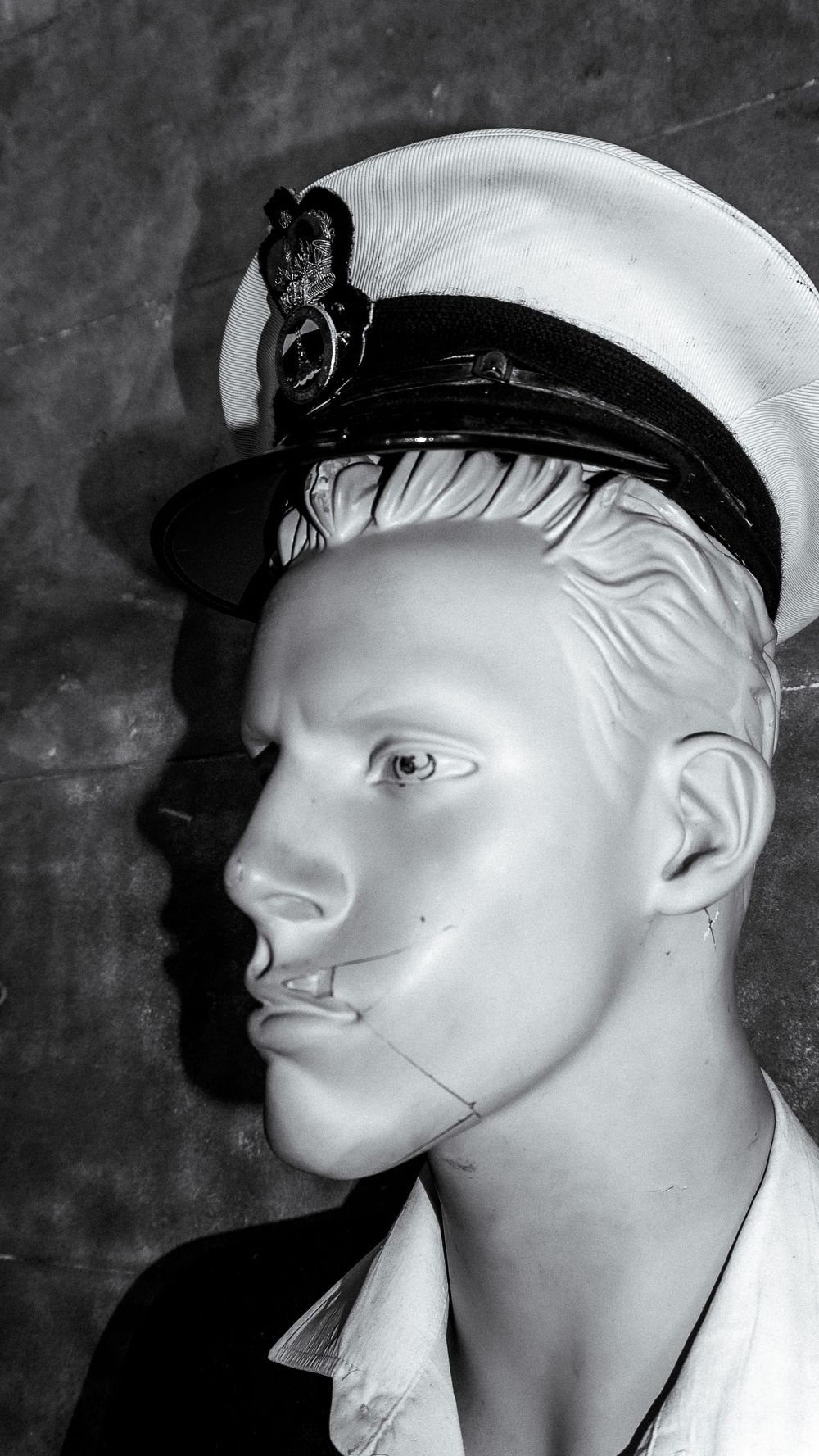 Series of white mannequin head profiles wearing sailor caps against a dark background.