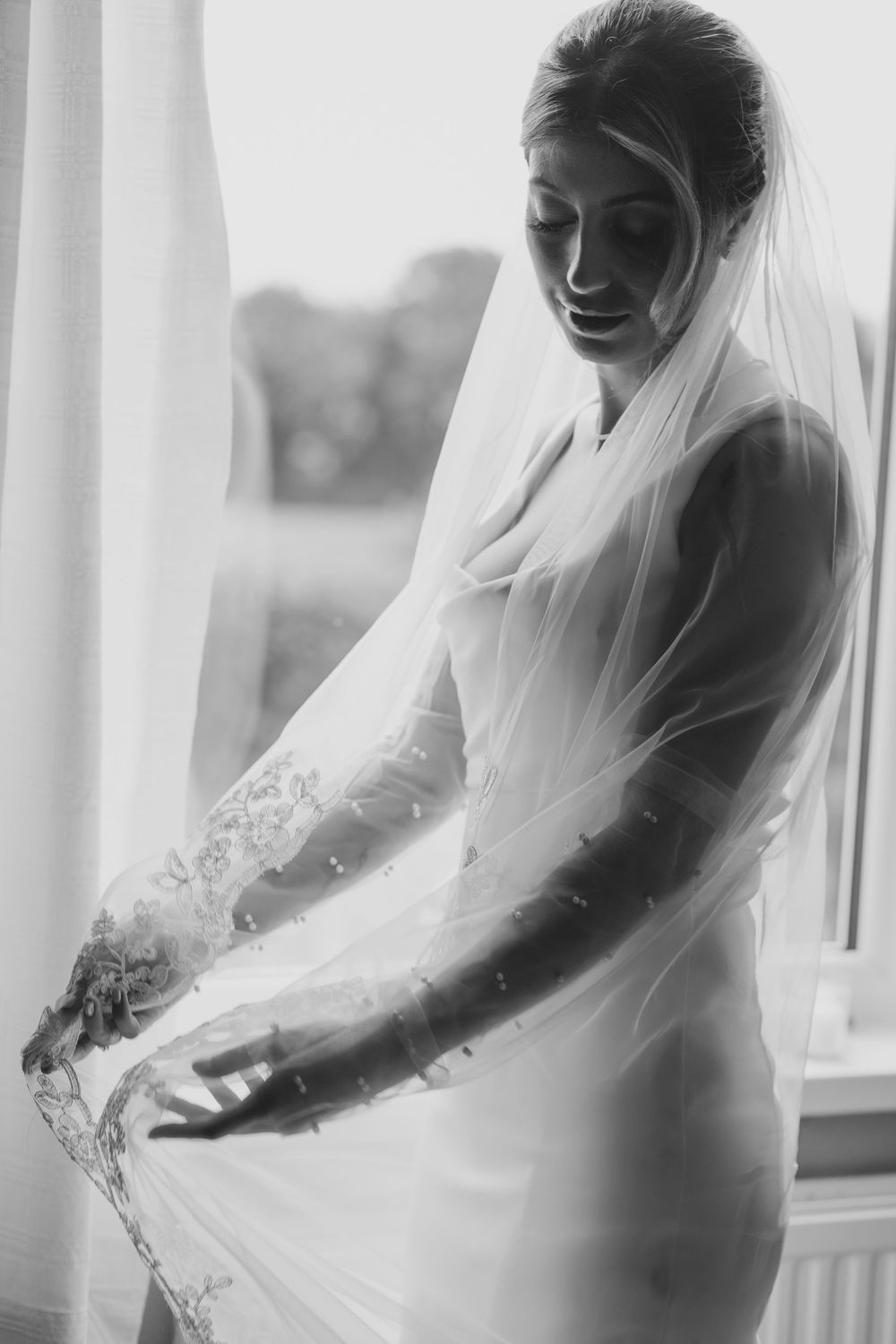 A black and white artistic sequence shows a bride in full wedding attire gazing down at her dress near a window.