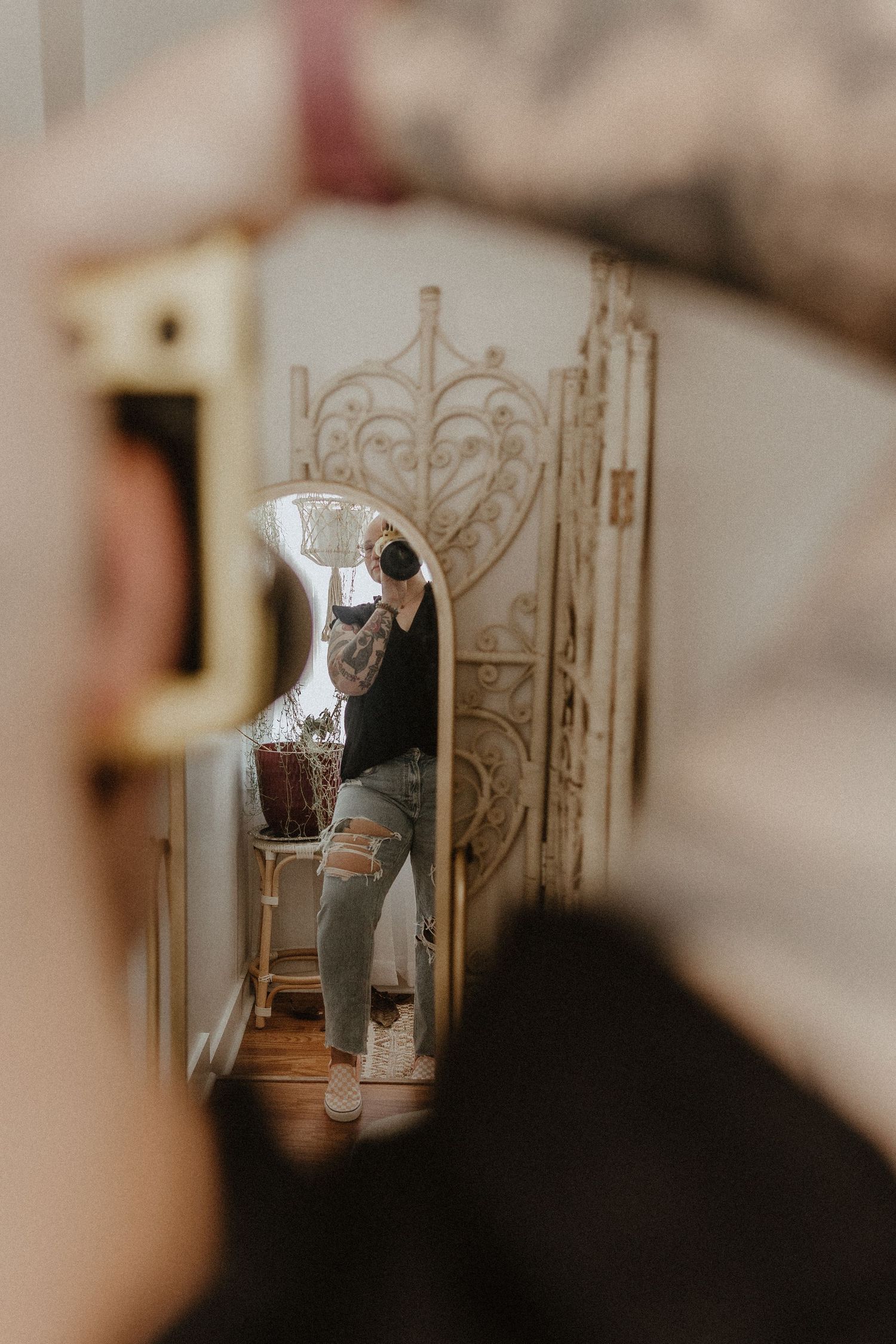 Artistic mirror reflection shot showing person seated in vintage-style room with ornate details.