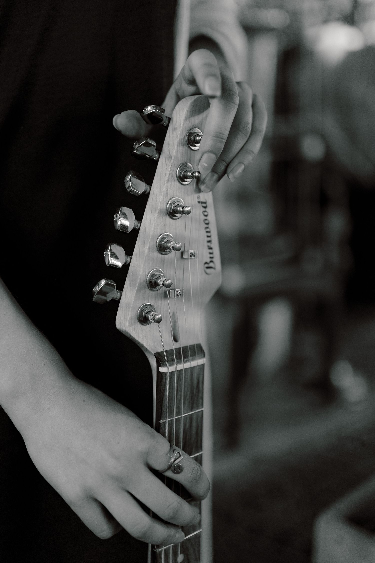 Black and white close-up shot of a Fender guitar headstock shown from multiple angles in a stylistic photo series.