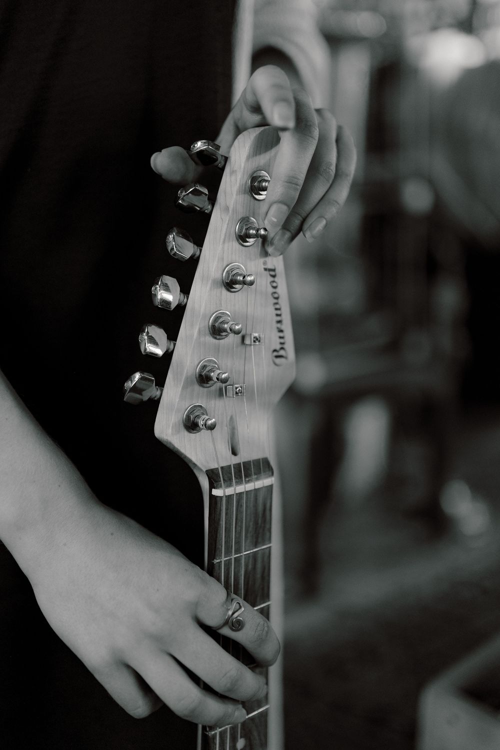 Black and white close-up shot of a Fender guitar headstock shown from multiple angles in a stylistic photo series.