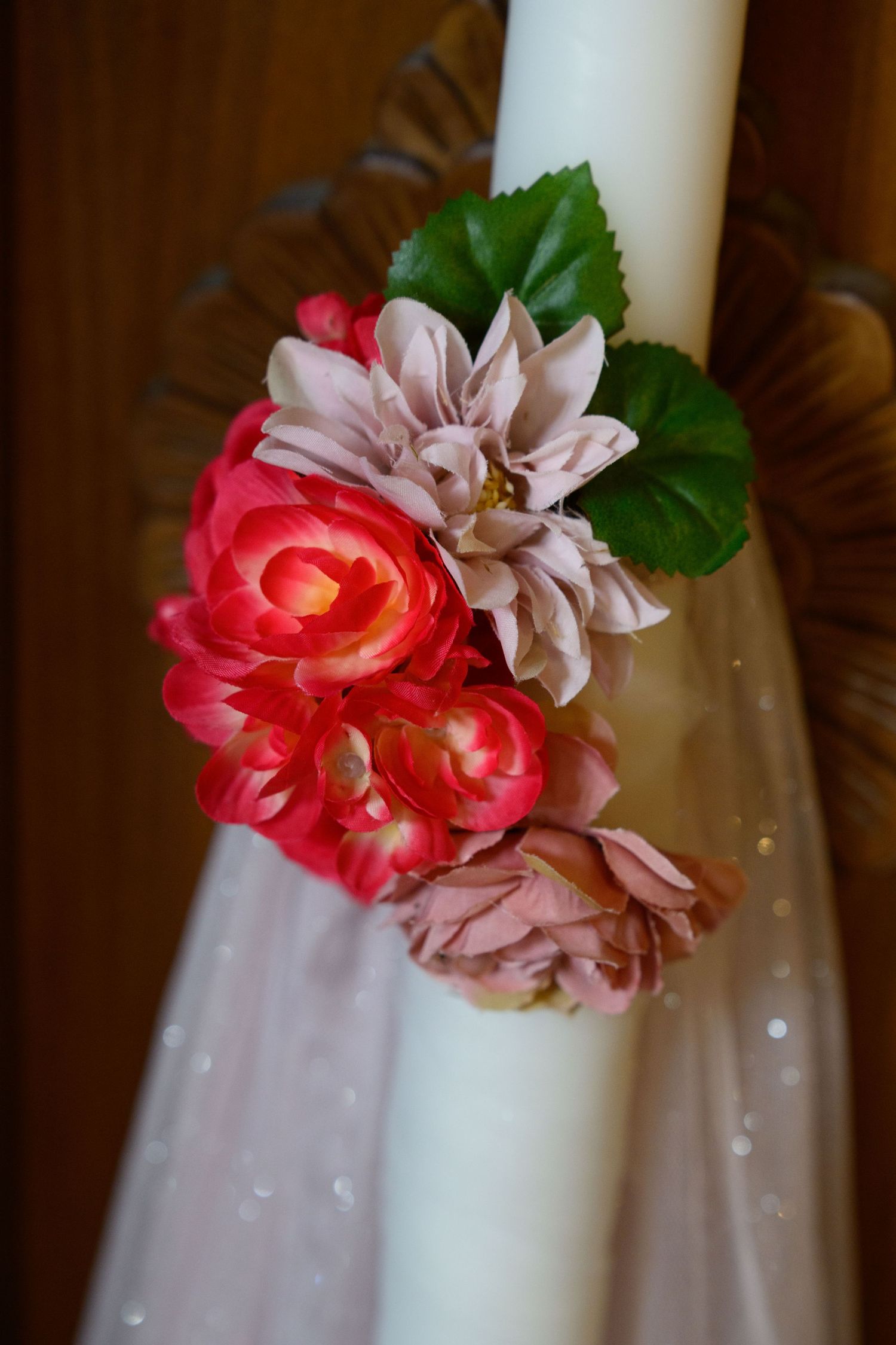 Decorative floral arrangement with pink and coral roses adorning a white candle.