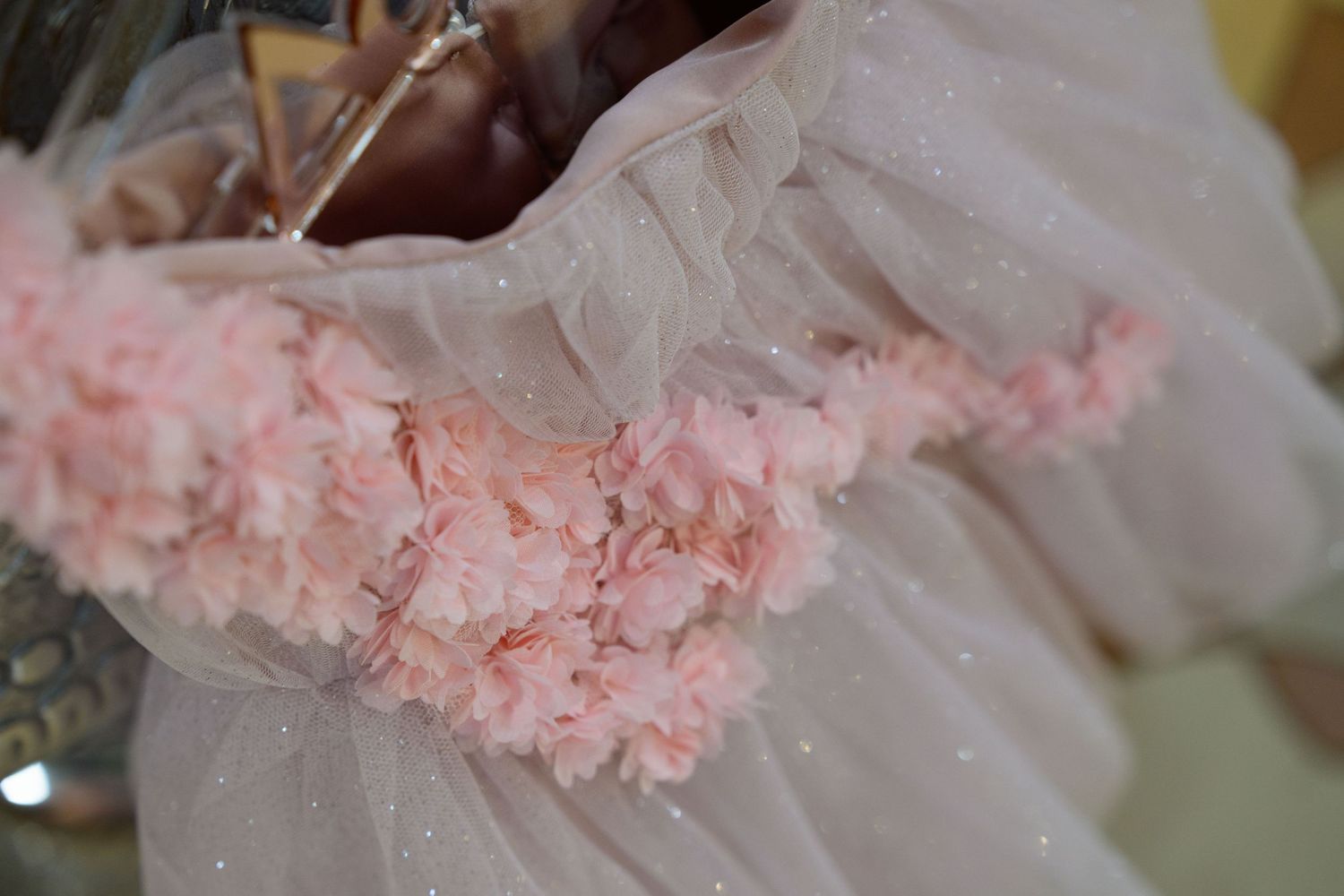 Close-up detail of pink floral embellishments on a tulle dress.