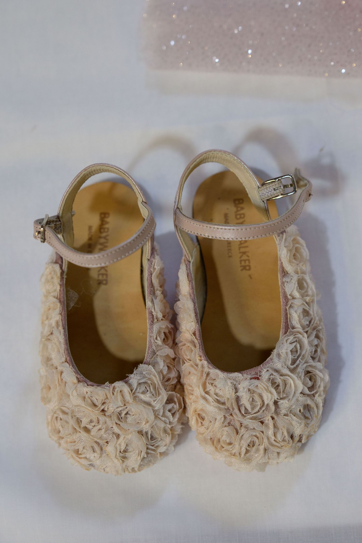 Cream-colored baby shoes decorated with delicate rose patterns.