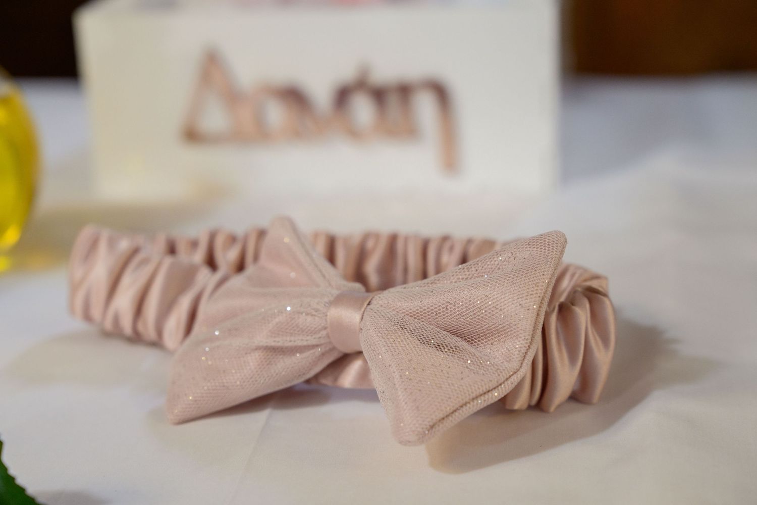 Blush pink silk bow tie laying on a white surface.