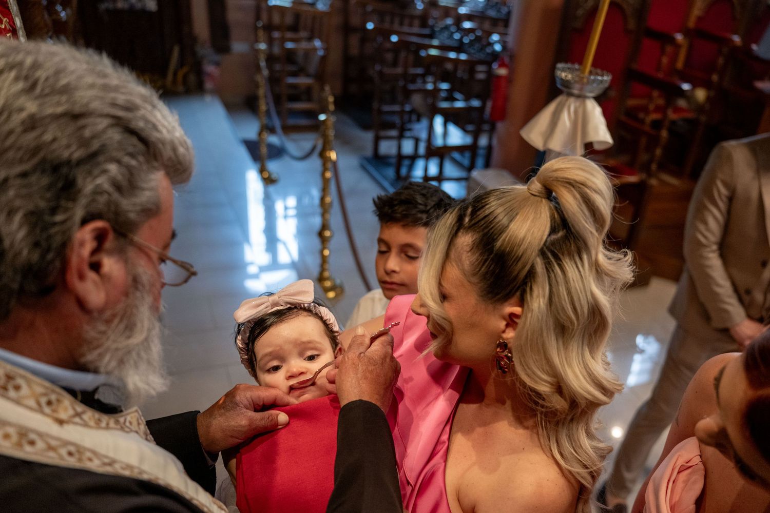 A religious ceremony taking place with participants gathered around a priest in traditional robes.