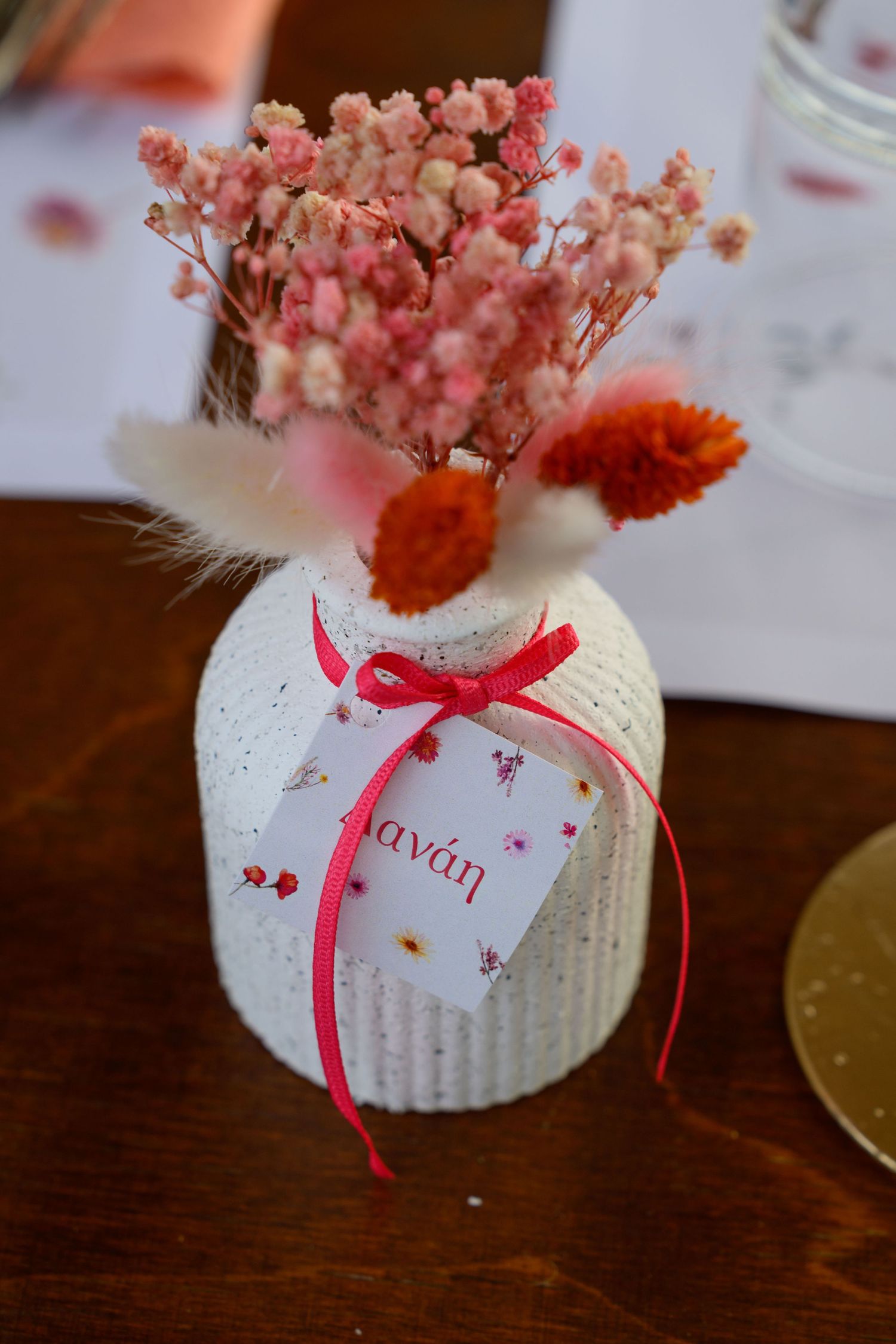 A decorative white vase labeled 'Kavan' filled with pink baby's breath and red dried flowers.