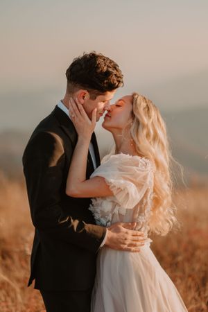 Alissa and andrew share a tender moment at their elopement, standing close in an outdoor setting with a hazy background.