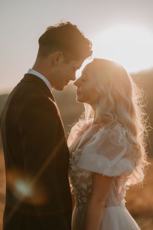 Alissa and Andrew stand closely at their sunset elopement, basking in warm, golden light with serene expressions.