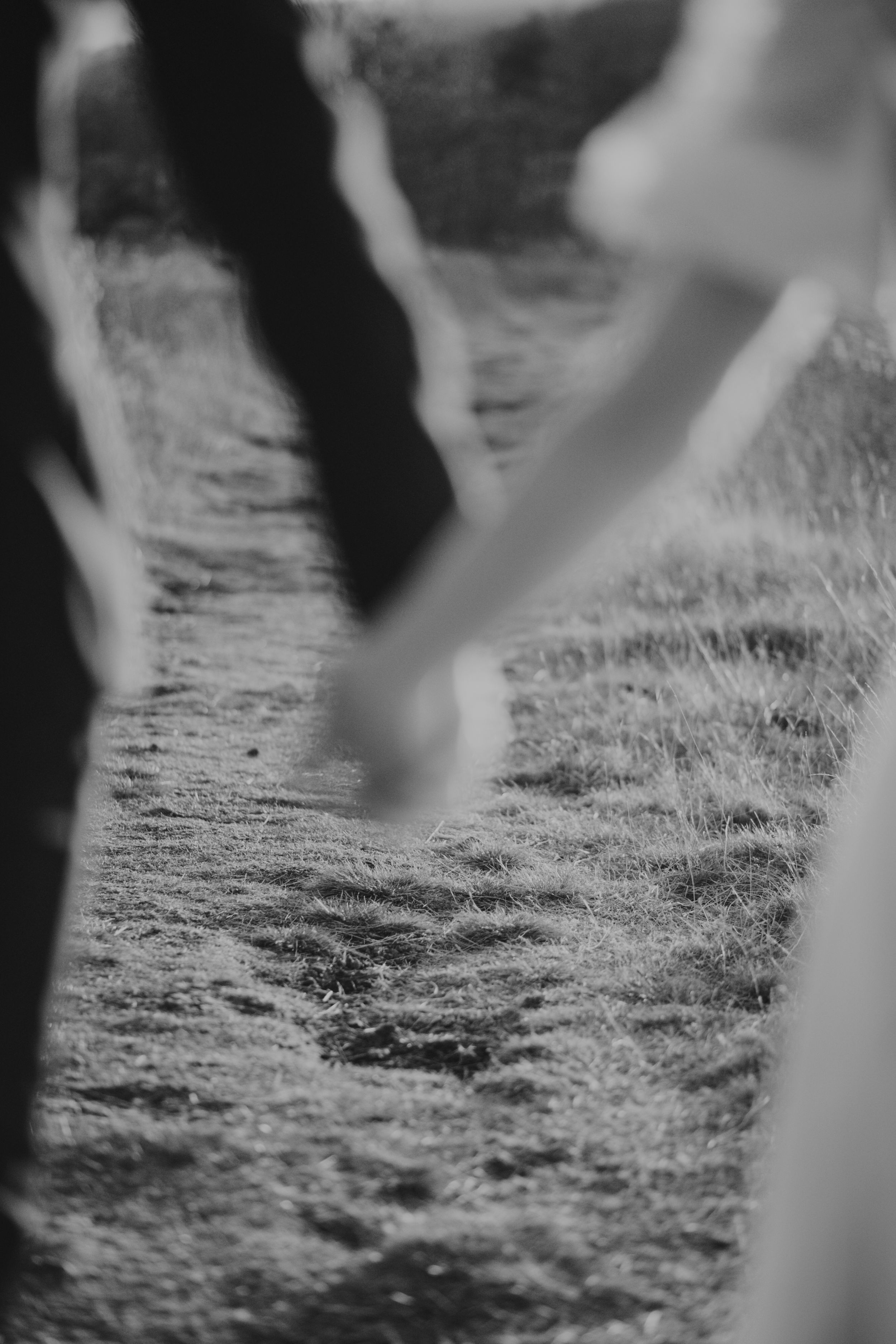 Black and white image of the couple holding hands, their hands intentionally out of focus.