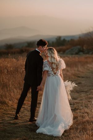 The bride and groom lean in close, facing away from the camera, after their sunset elopement ceremony.
