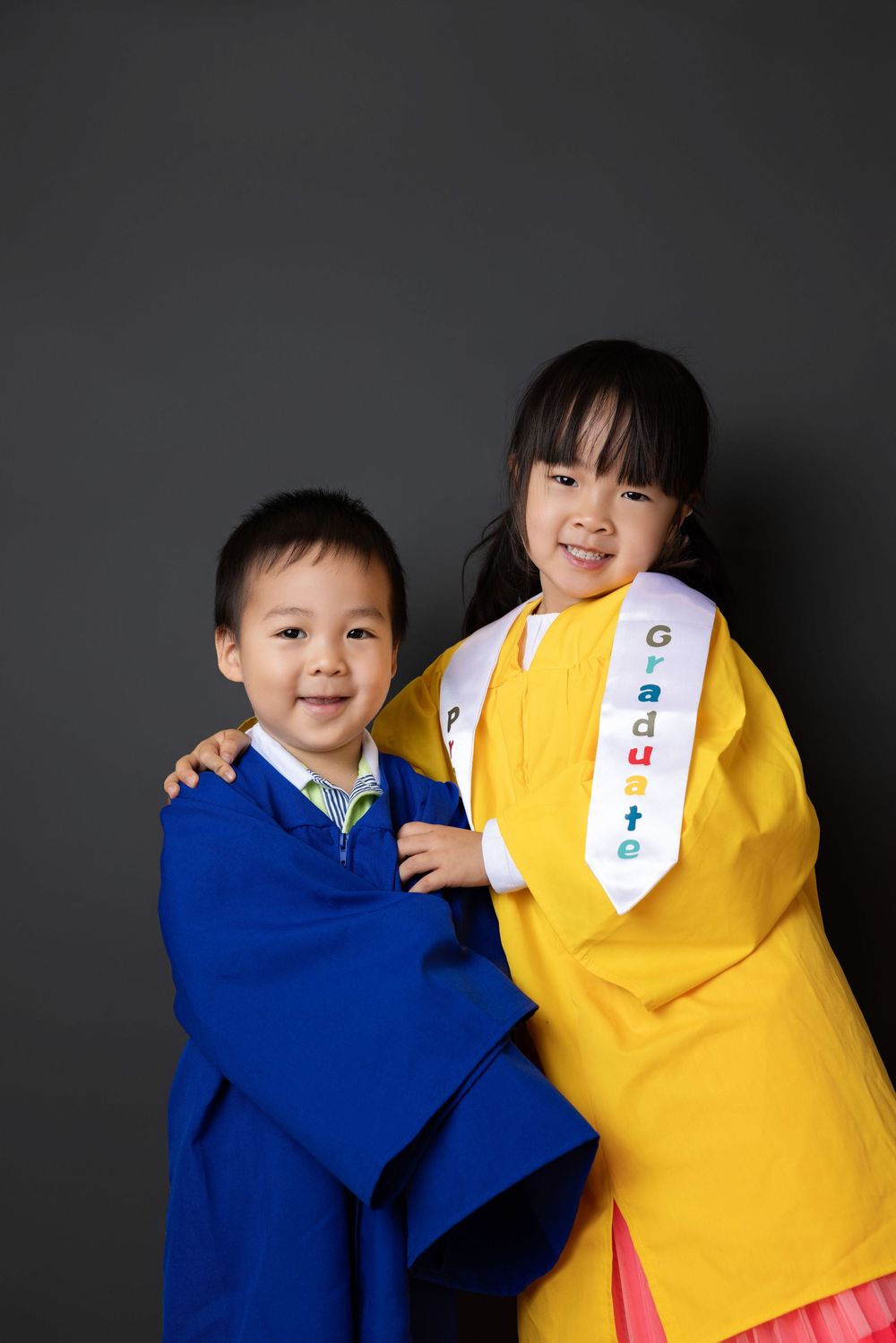 Two children in contrasting blue and yellow shirts share playful interactions against a dark background.