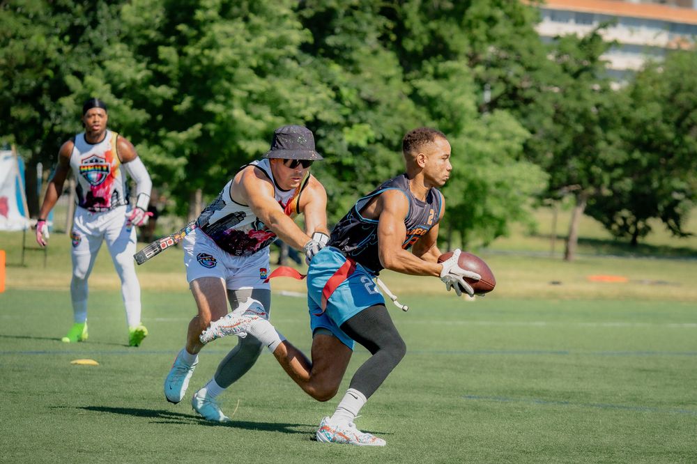 An athlete from San Diego Drip runs downfield with the football while an ATX Heat athlete pulls the ball carrier's flags