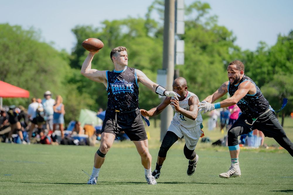 The quarterback from the Chicago Freeze begins to throw the ball while an opponent attempts to pull his flags to sack the quarterback