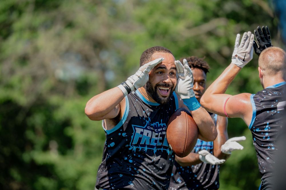 An athlete from the Chicago Freeze celebrates a score with a teammate at Pride Bowl hosted by the National Gay Flag Football League and CMSA