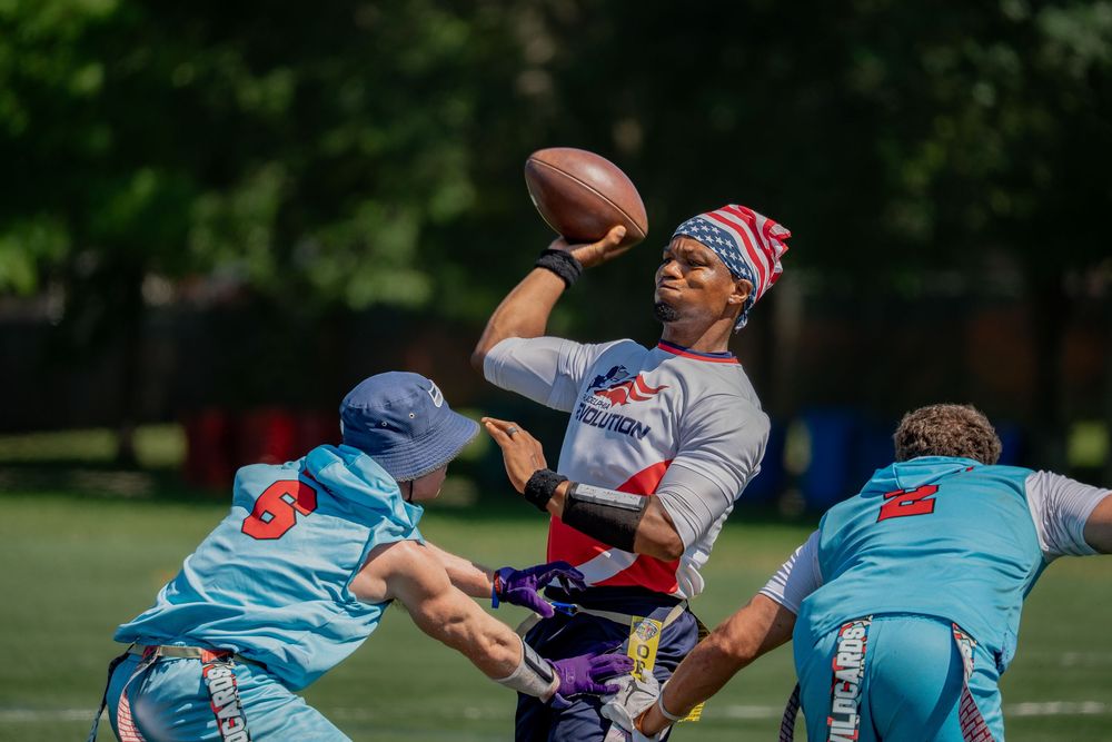 The Philadelphia Revolution quarterback makes a pass while two Washington Wildcards players attempt to sack at Pride Bowl