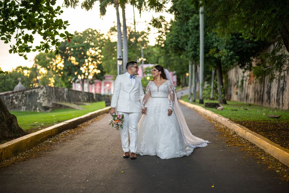 Wedding couple holding hands while walking along a tree-lined path in Central Park during golden hour.