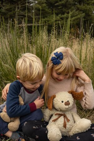 Siblings hugging and looking at their stuffed animals.