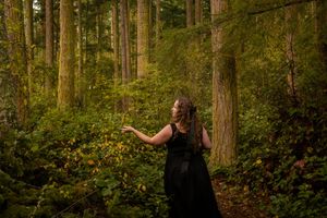 Woman in the forest reaching out to the plants around her.
