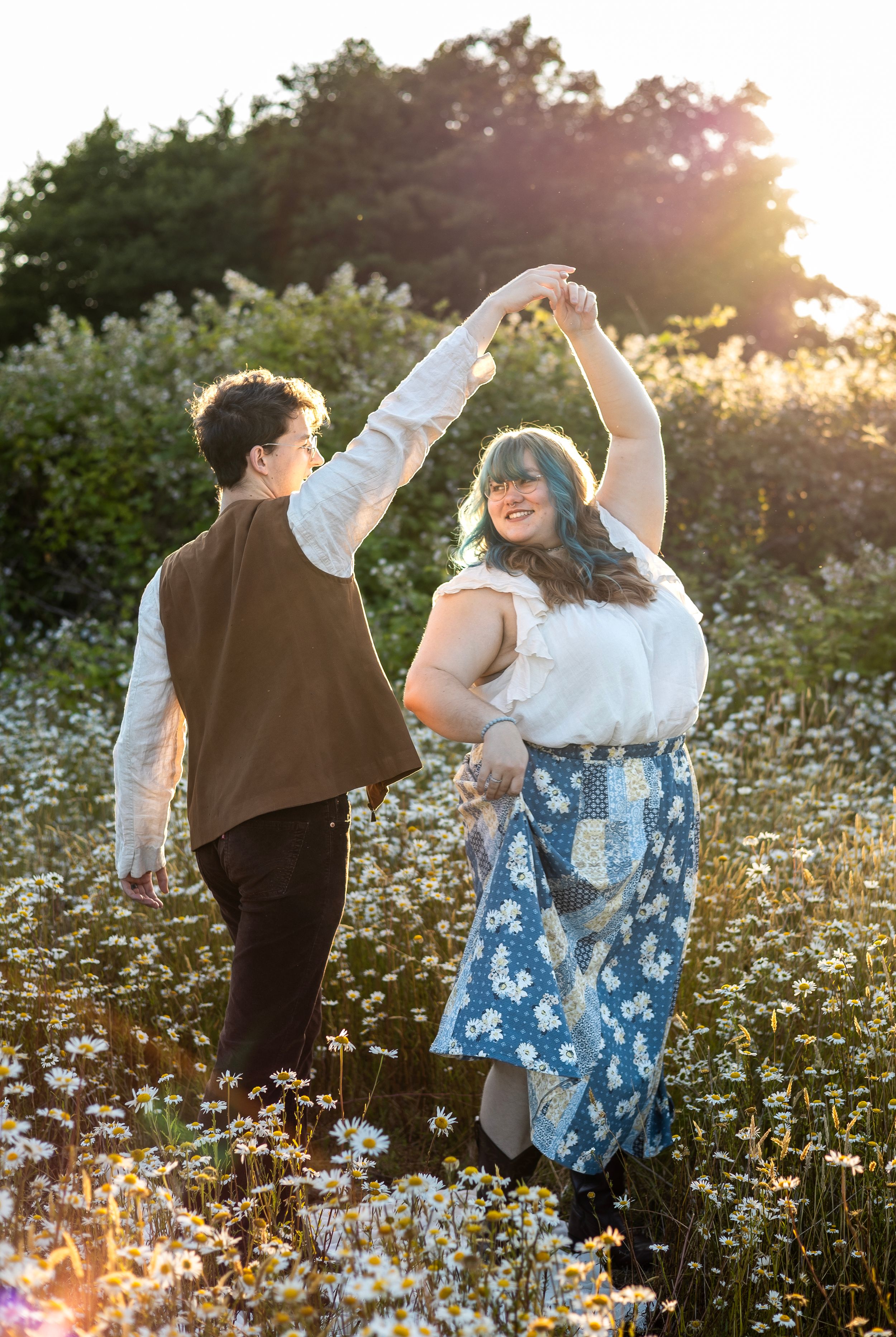 Couple dancing in a field of daisies during golden hour.