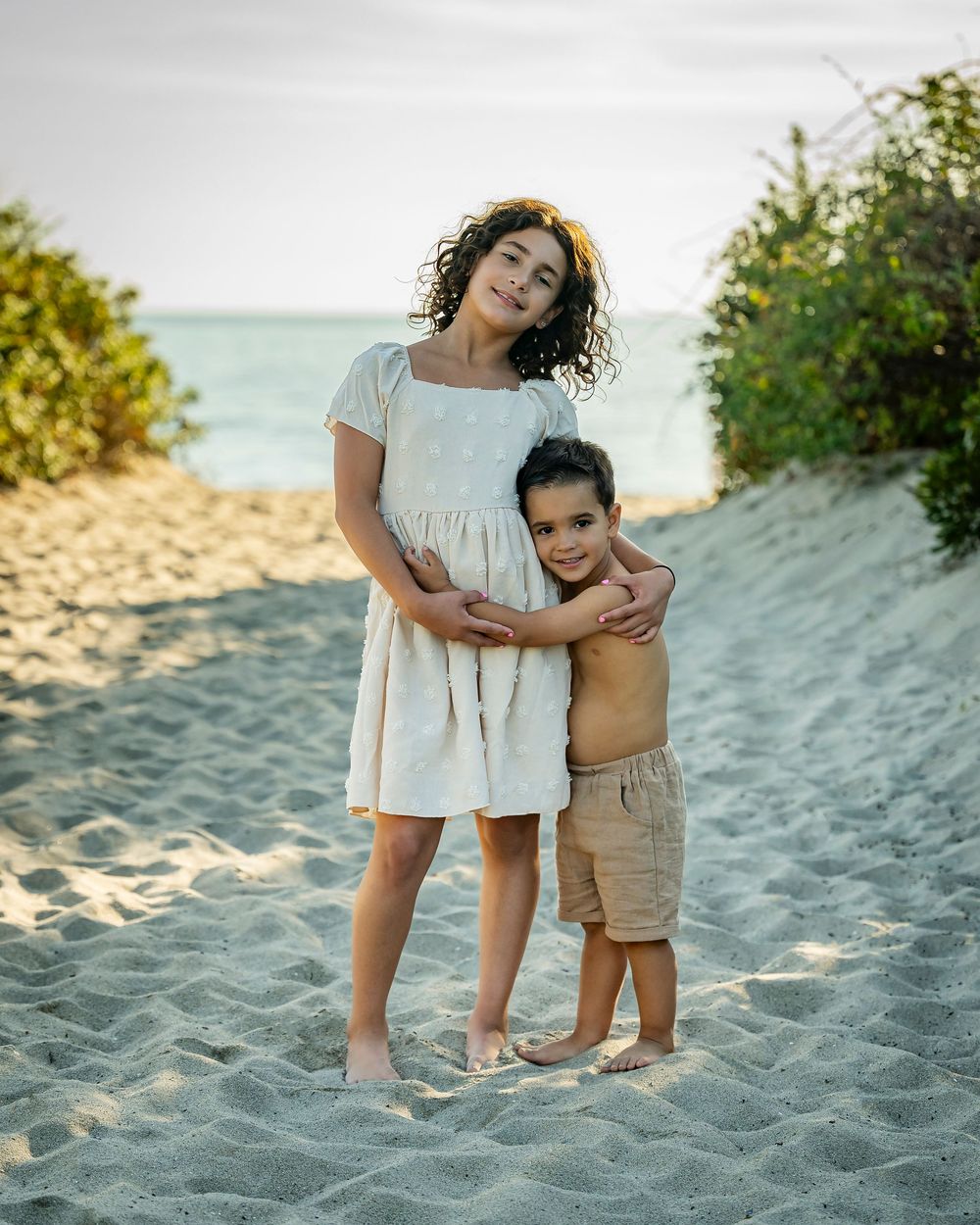 A portrait photograph of a young boy and girl on the beach