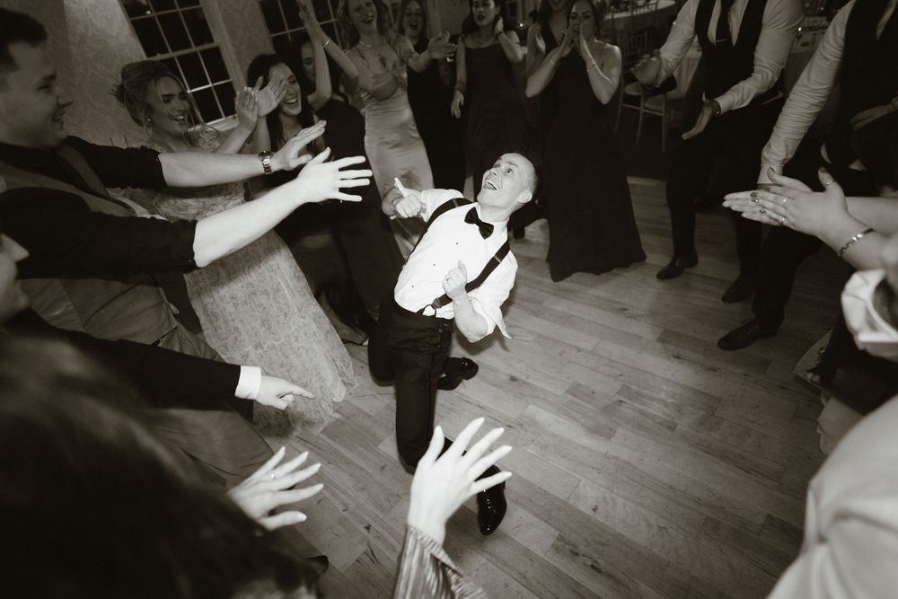 Black and white photo of a man dancing energetically at a wedding reception at Rathsallagh Country House , Co. Wicklow