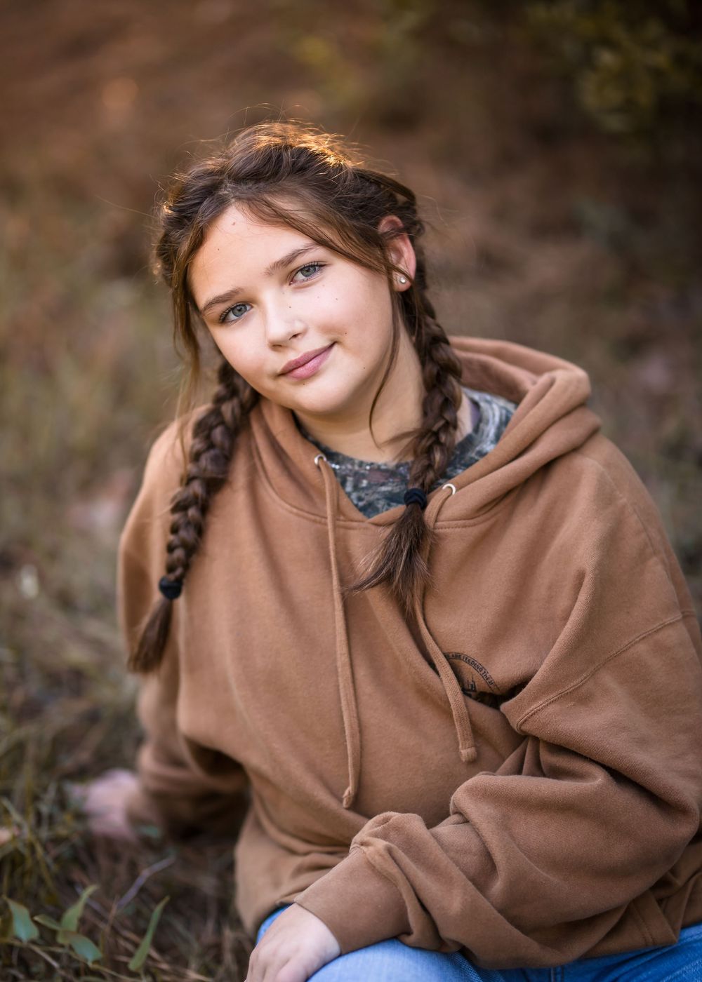 A person in a brown hoodie poses outdoors against a natural blurred background in a series of casual portraits.