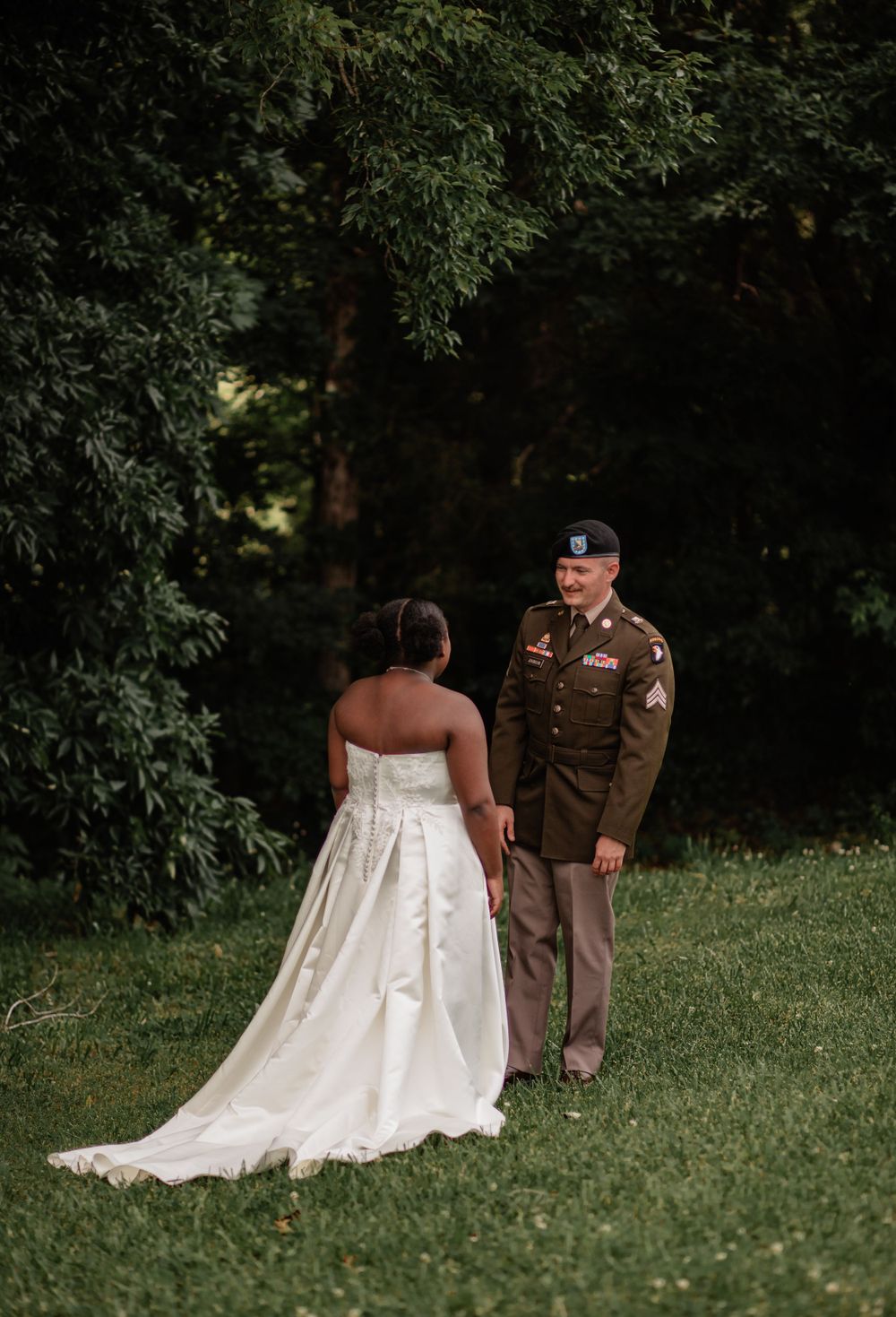 A tender moment between a couple on their wedding day, surrounded by lush greenery.