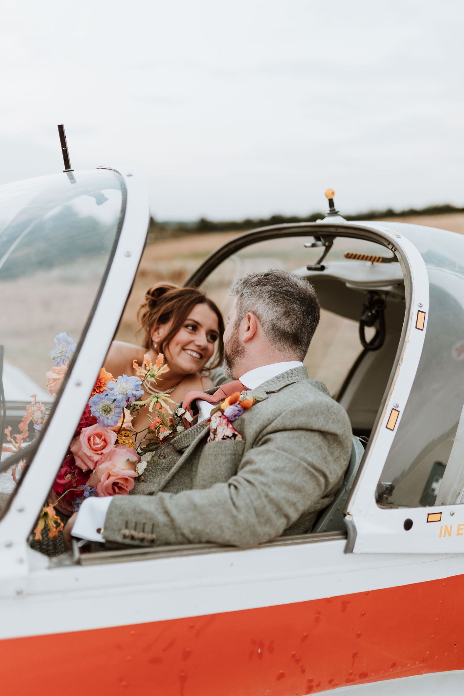A couple shares an intimate moment inside a small aircraft with orange and white exterior details.