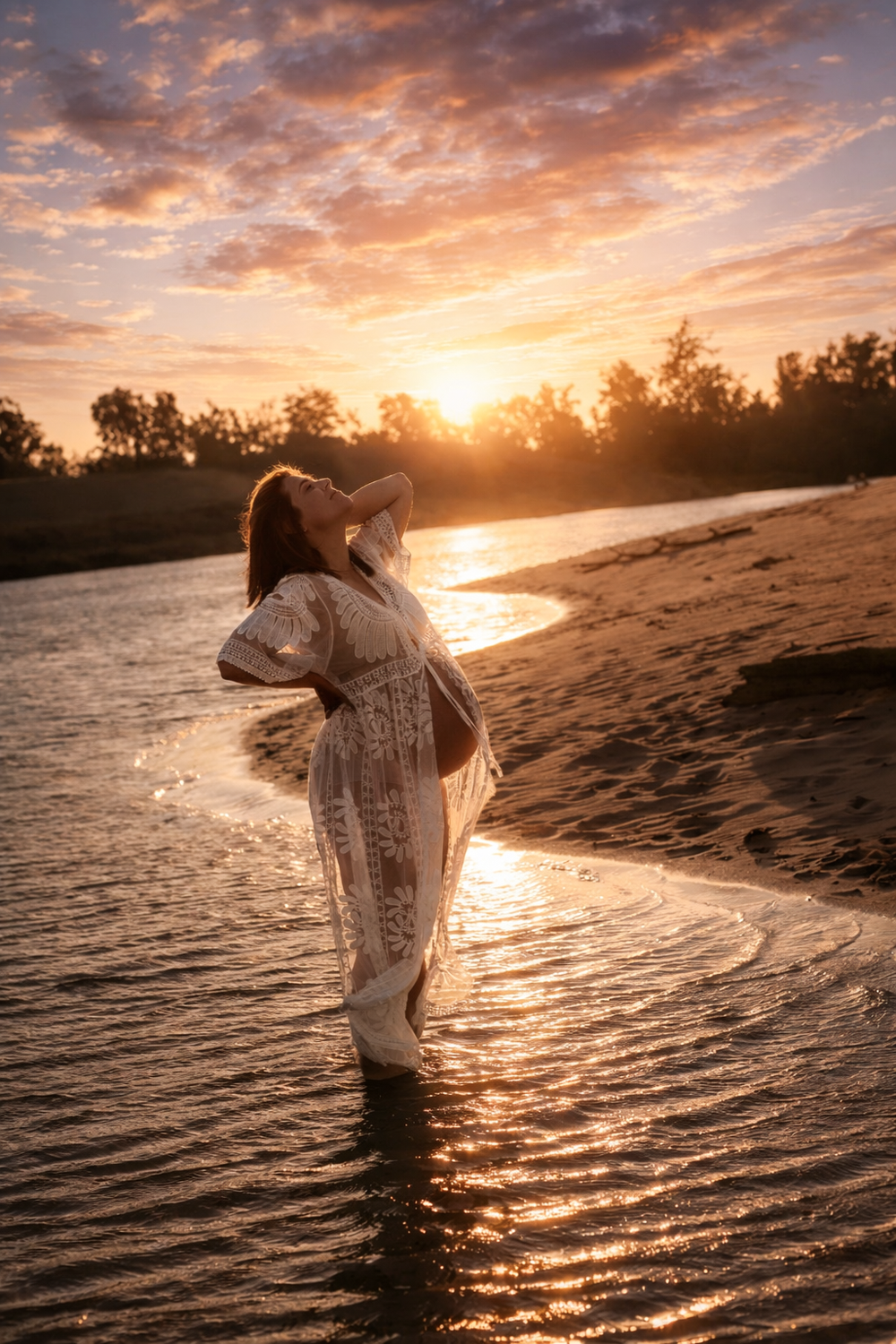 Figure in white dress dancing at sunset on beach with dramatic orange sky and water reflections.