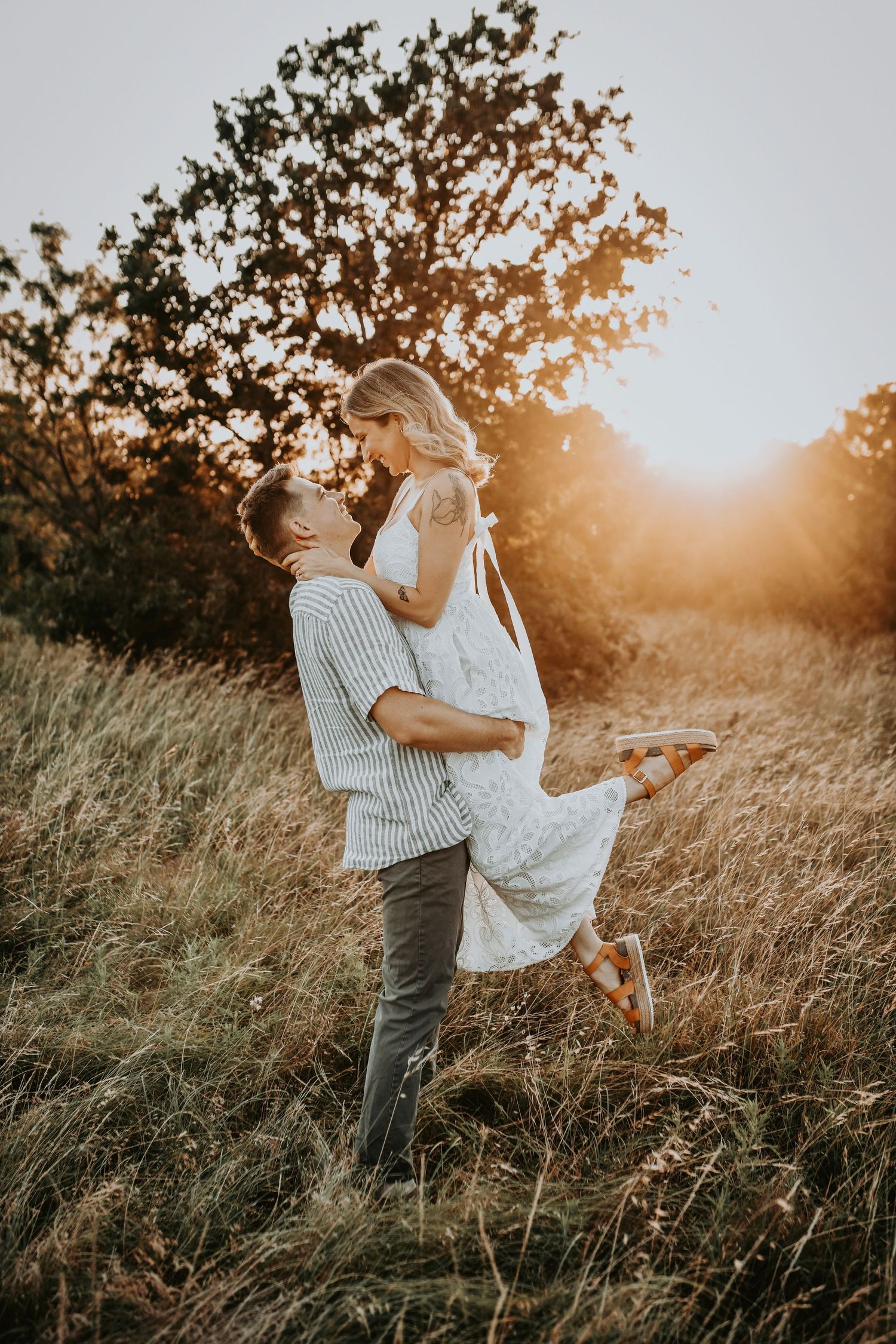 Excited couple lifting her during a sunset engagement session, captured in a joyful, candid style