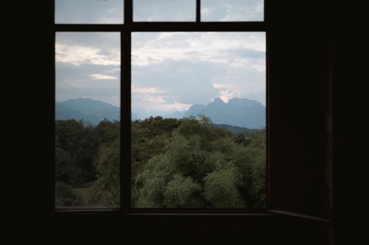 Le sagome scure dei telai delle finestre si affacciano sulle Dolomiti al tramonto.