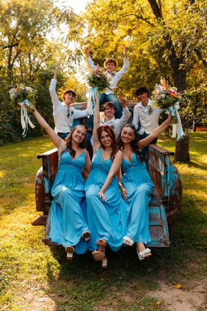 Bridesmaids in matching blue dresses pose joyfully under golden autumn trees.wedding photography st louis