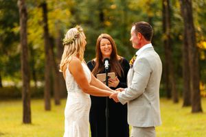 An outdoor wedding ceremony taking place in a sunlit forest setting with autumn colors.wedding photography st louis