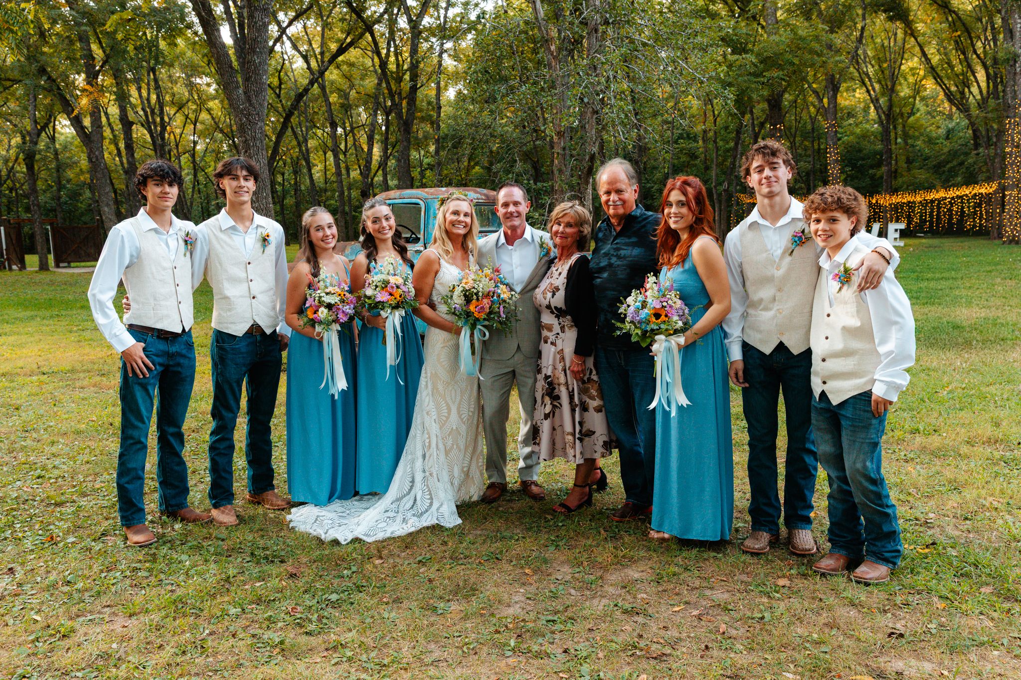 Wedding party poses outdoors in coordinated blue and white attire surrounded by autumn trees. wedding photography st louis