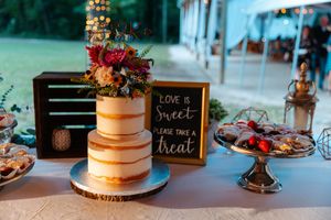 A rustic wedding cake display with fresh flowers and a chalkboard sign reading 'Love is sweet' on a dessert table.wedding photography st lou