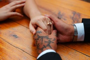 Close-up details of hands and rings on wooden surface showing wedding jewelry.wedding photography st louis