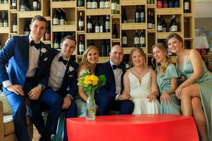 Wedding party posing together in a wine bar, bride in white gown with groom and bridesmaids in teal dresses.