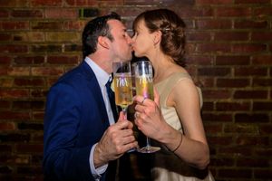 Couple in formal attire sharing champagne toast against brick wall backdrop. wedding photography st louis