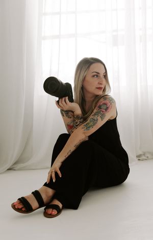 A series of artistic photos showing someone in black clothing reclining on a white floor with visible tattoos.
