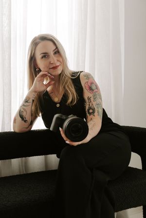 Person in black dress poses gracefully on dark surface in front of white curtains in artistic photo series.