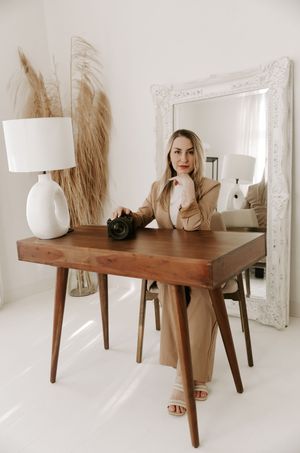 Minimalist interior design featuring wooden console table with white ceramic vases and decorative pampas grass against white wall.