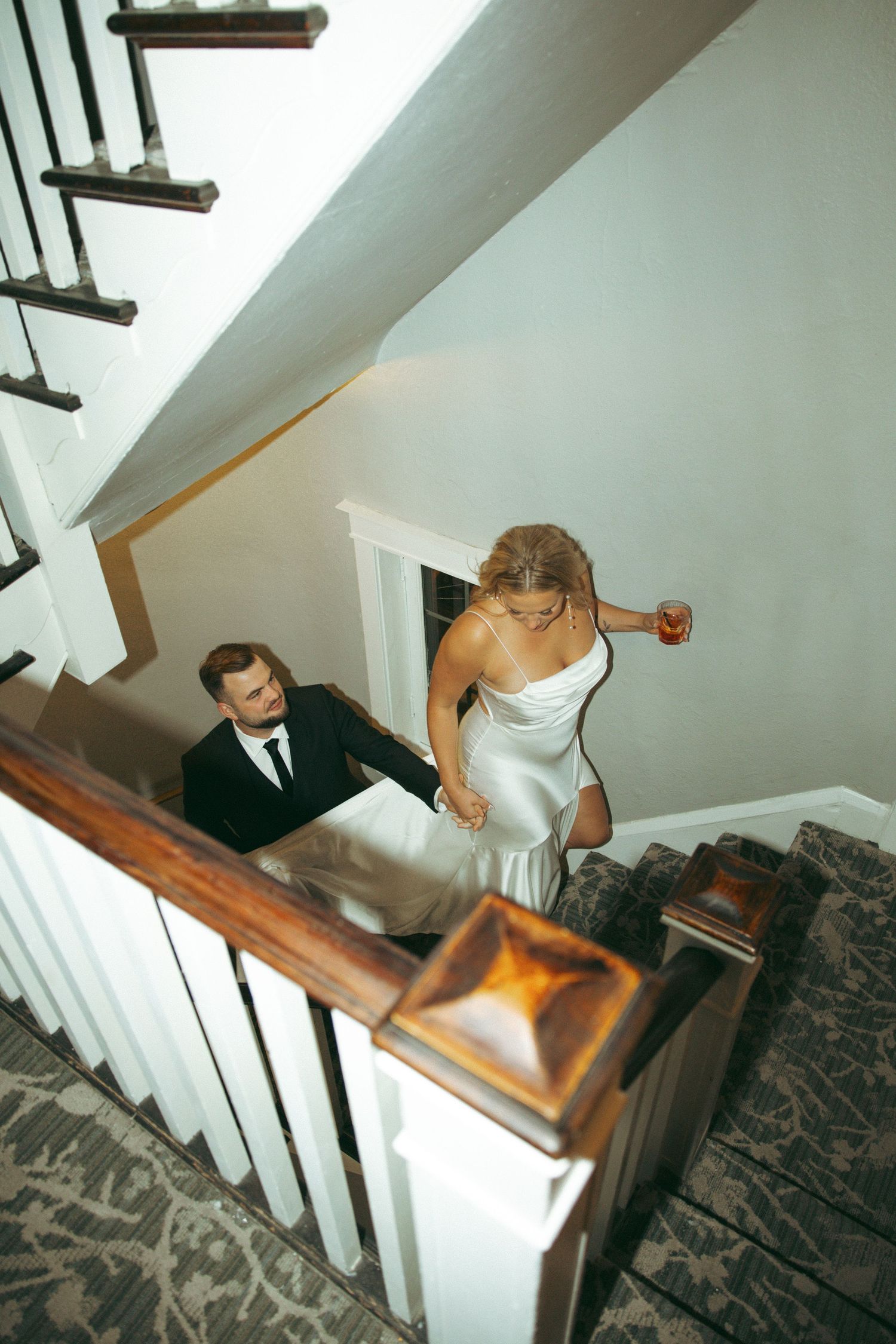 A couple in formal wedding attire descends a staircase in a series of four connected photos showing their movement.