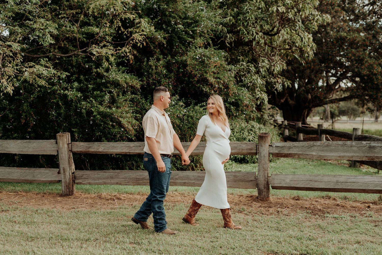 A couple walks hand in hand through a serene park setting during an outdoor gladstone photography session.