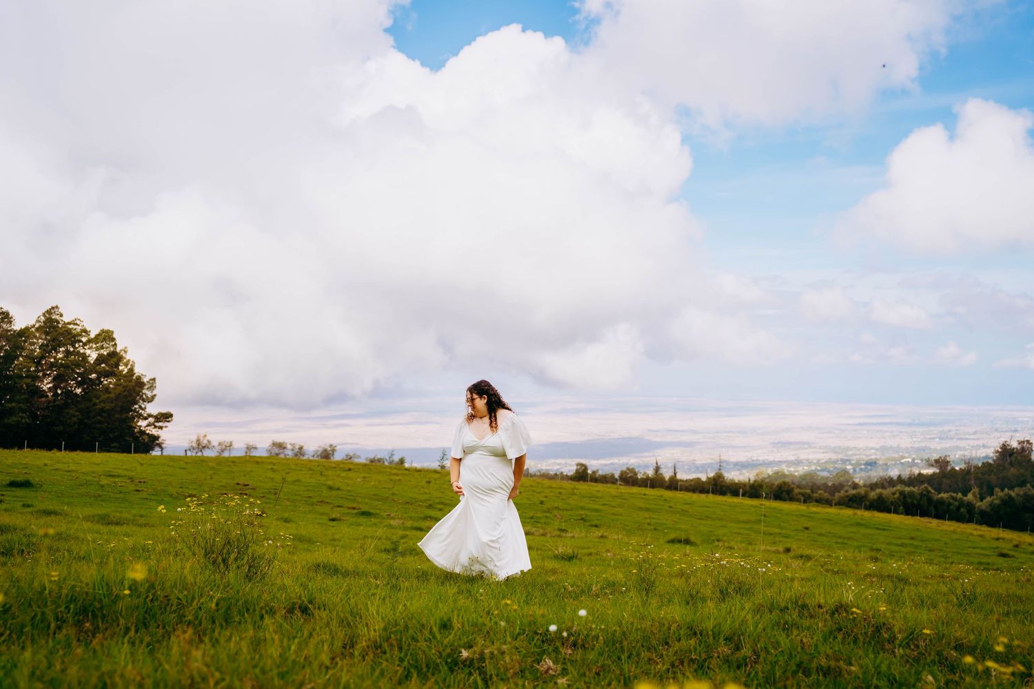 Rolling green hills and cloudy sky create a pastoral landscape panorama senior photos for seabury senior maui hawaii
