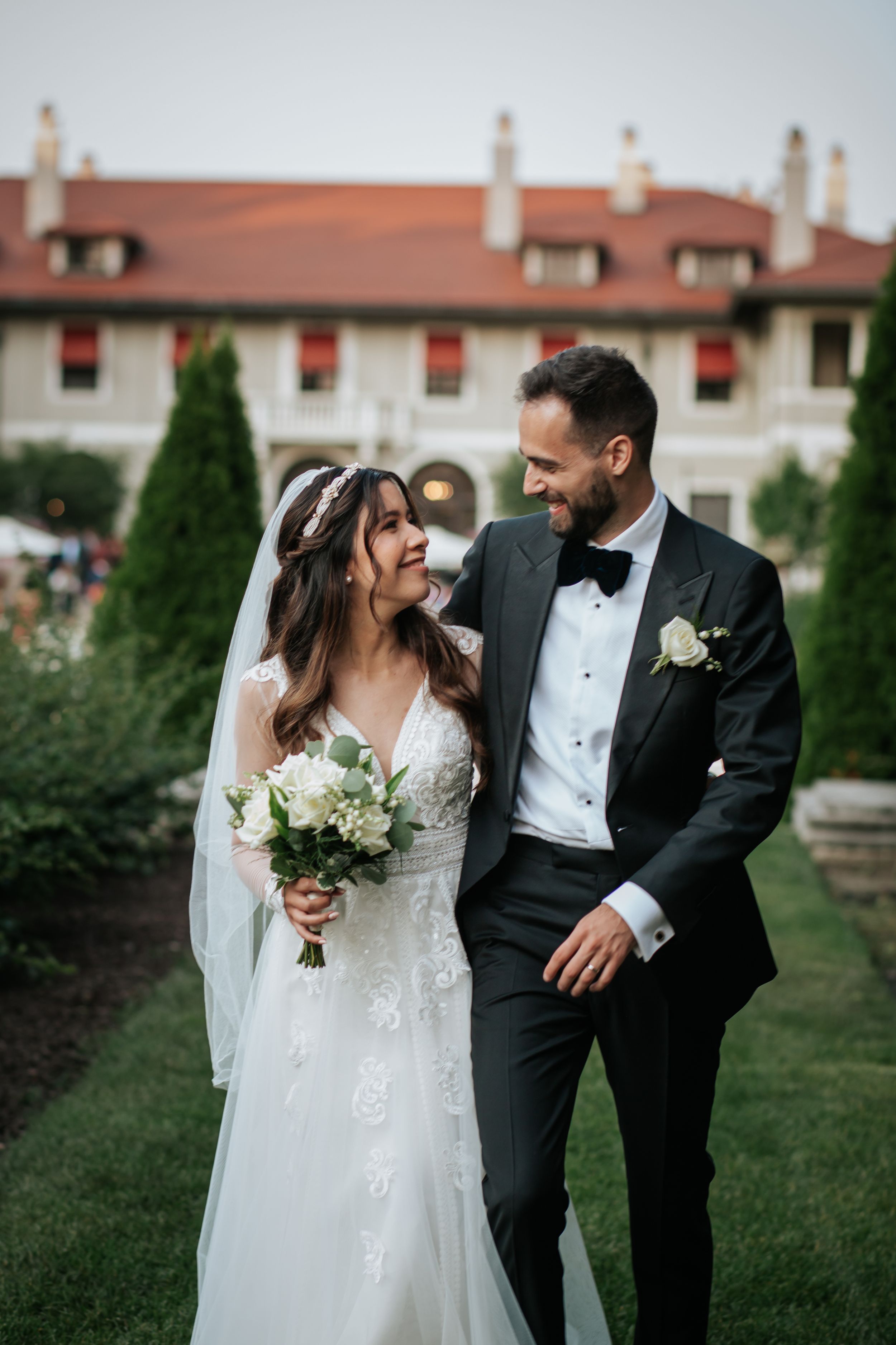 A bride and groom share romantic moments on their wedding day in front of a brick building with white trim.
