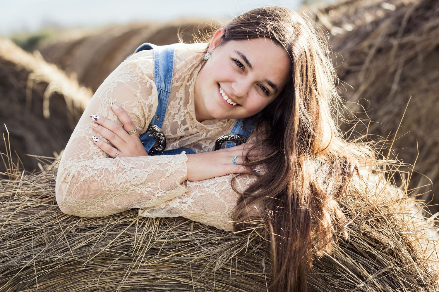 Senior session in golden sunlit field with tall grass.