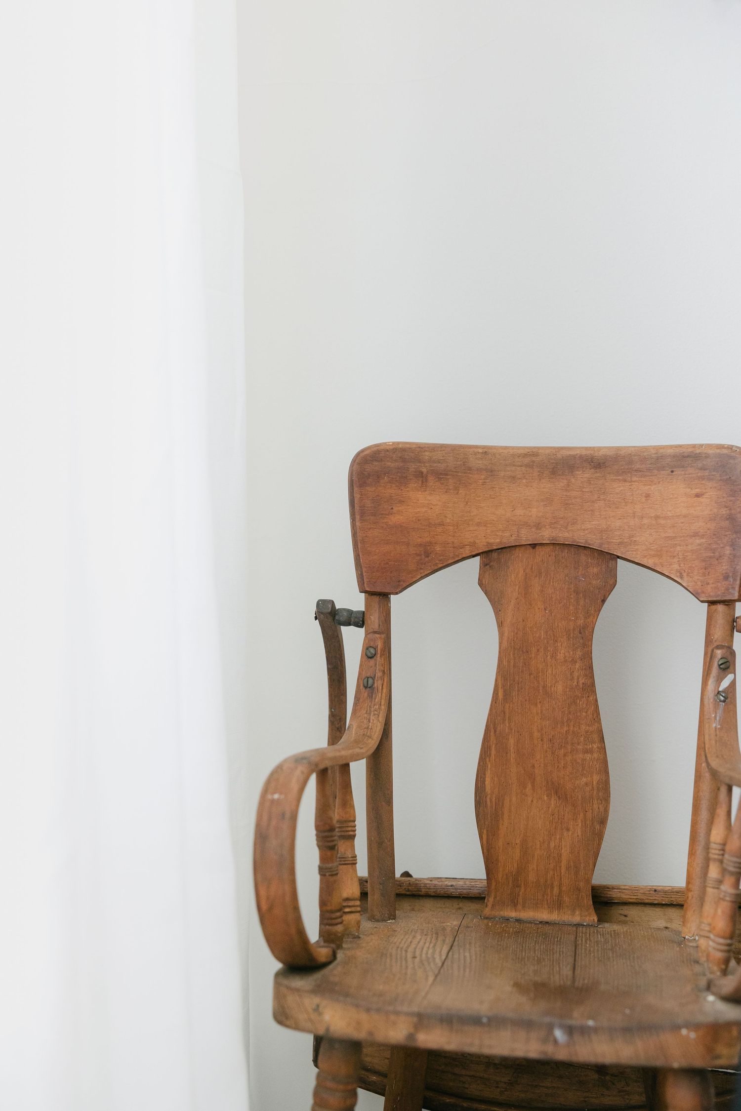 Close-up view of a vintage wooden armchair with curved details and natural patina showing its age and character.