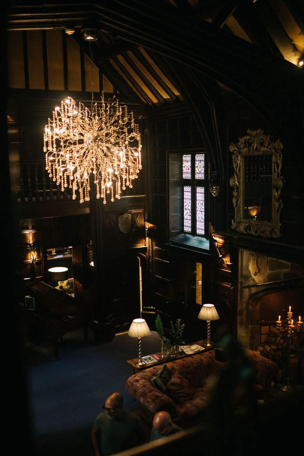 Elegant dark room with dramatic chandelier lighting and vintage furniture creates moody atmosphere.