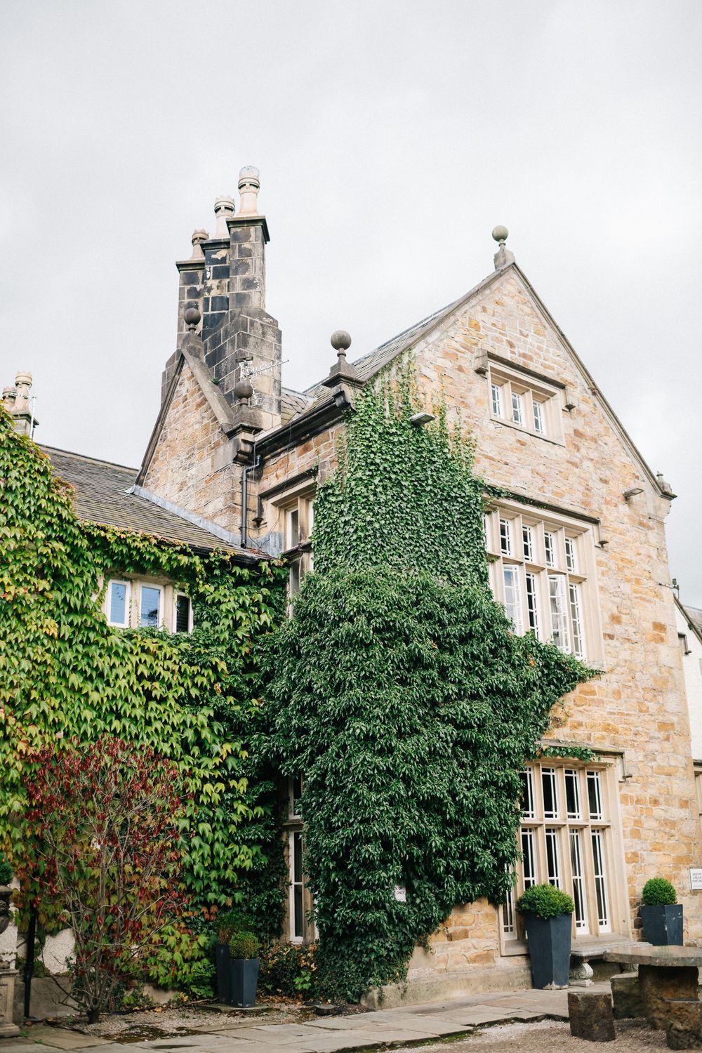 Historic stone mansion with ivy-covered walls and traditional architecture photographed on an overcast day.